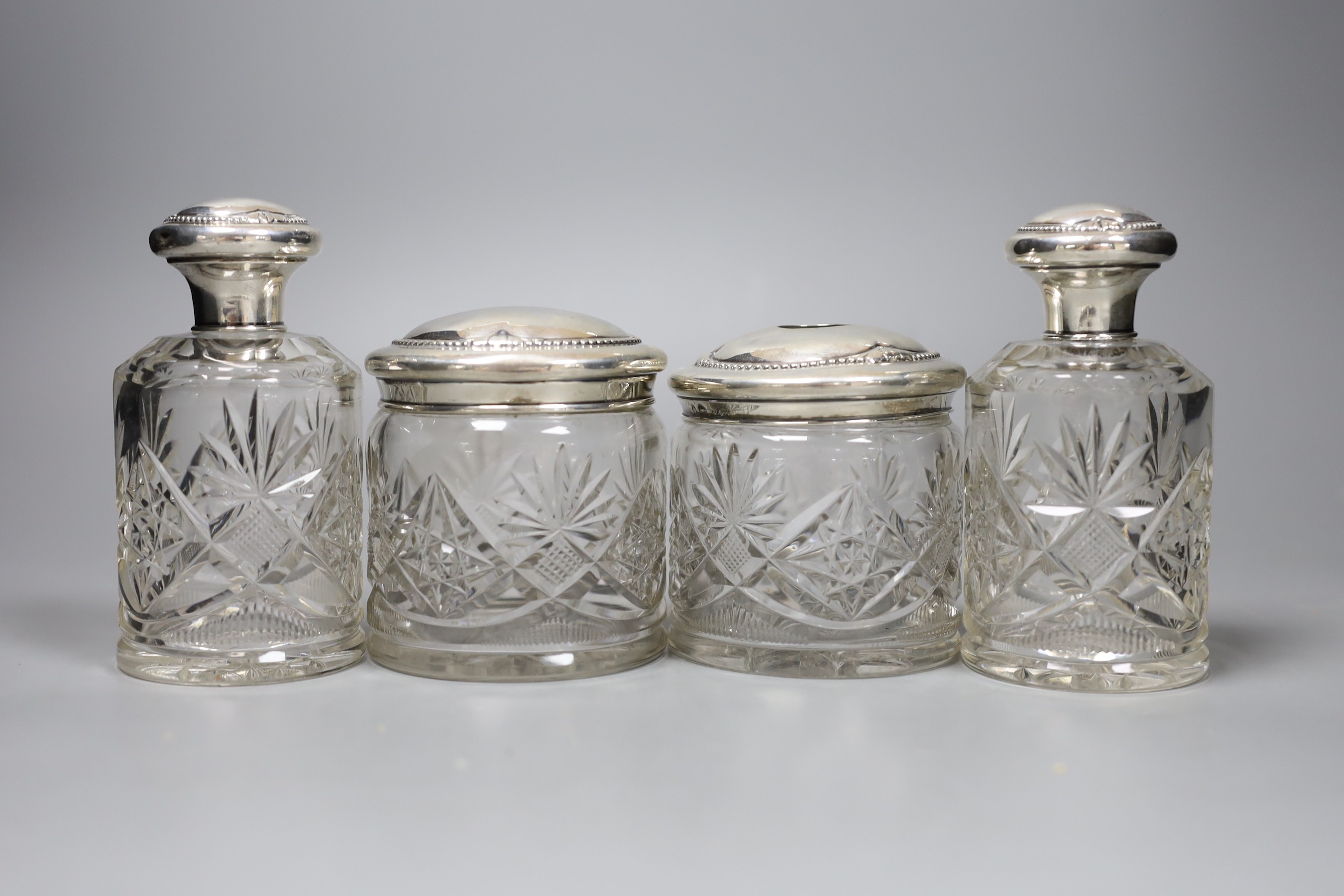 A pair of Continental white metal mounted cut glass scent bottles, 12.5cm and two matching toilet jars